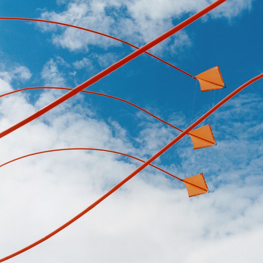 Orange kites flying in a blue sky